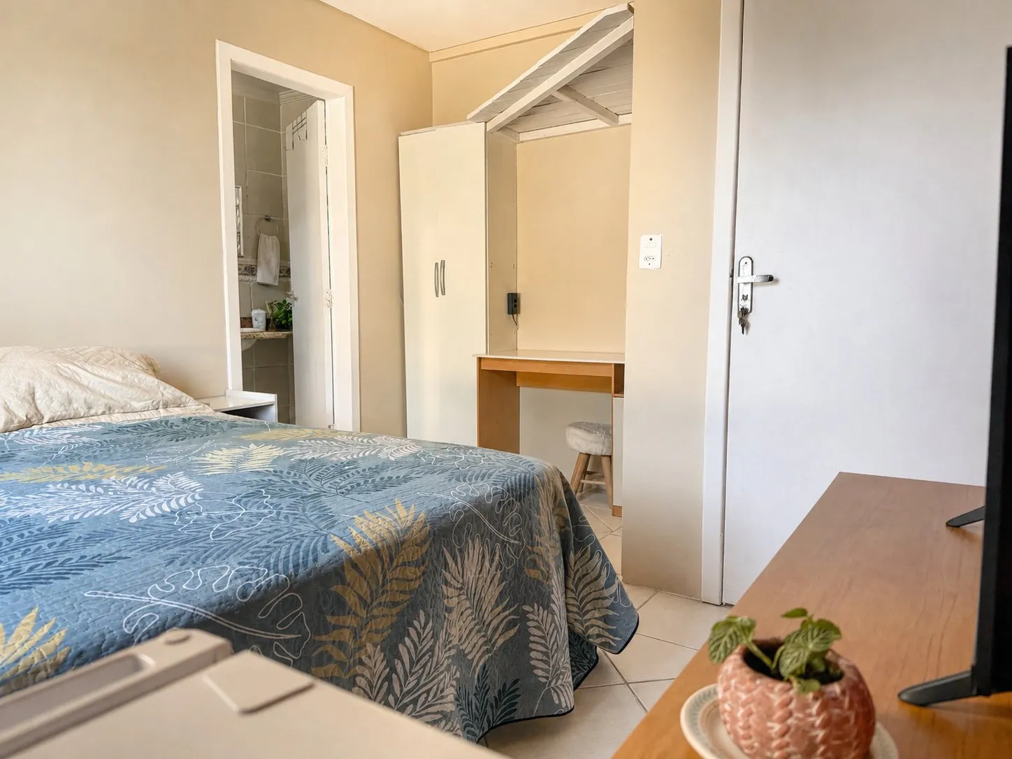Cama da Suíte Santinho com escrivaninha ao fundo